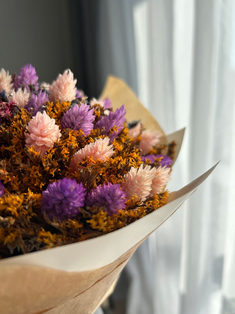 A colorful close-up of a bouquet featuring vibrant dried flowers in purple, pink, and orange hues.
